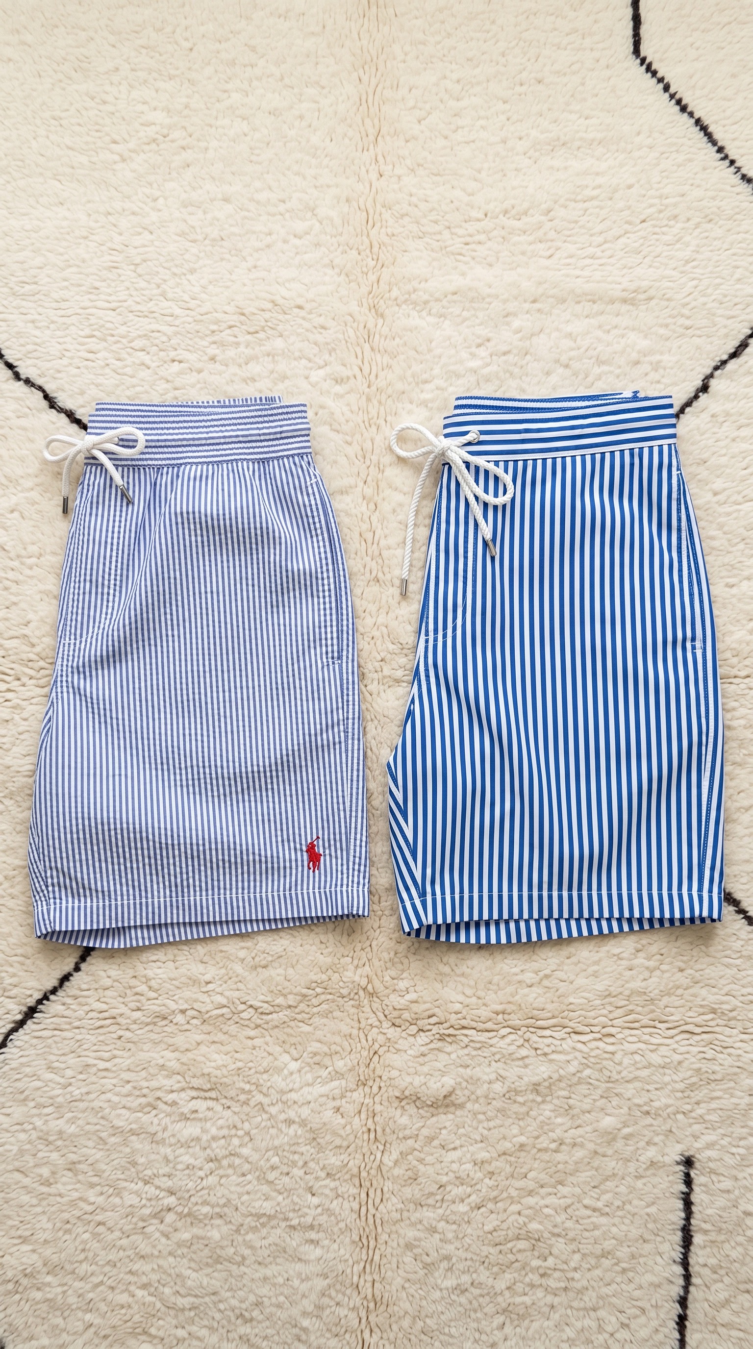 Product flat-lay of two pairs of striped swim shorts on a rug
