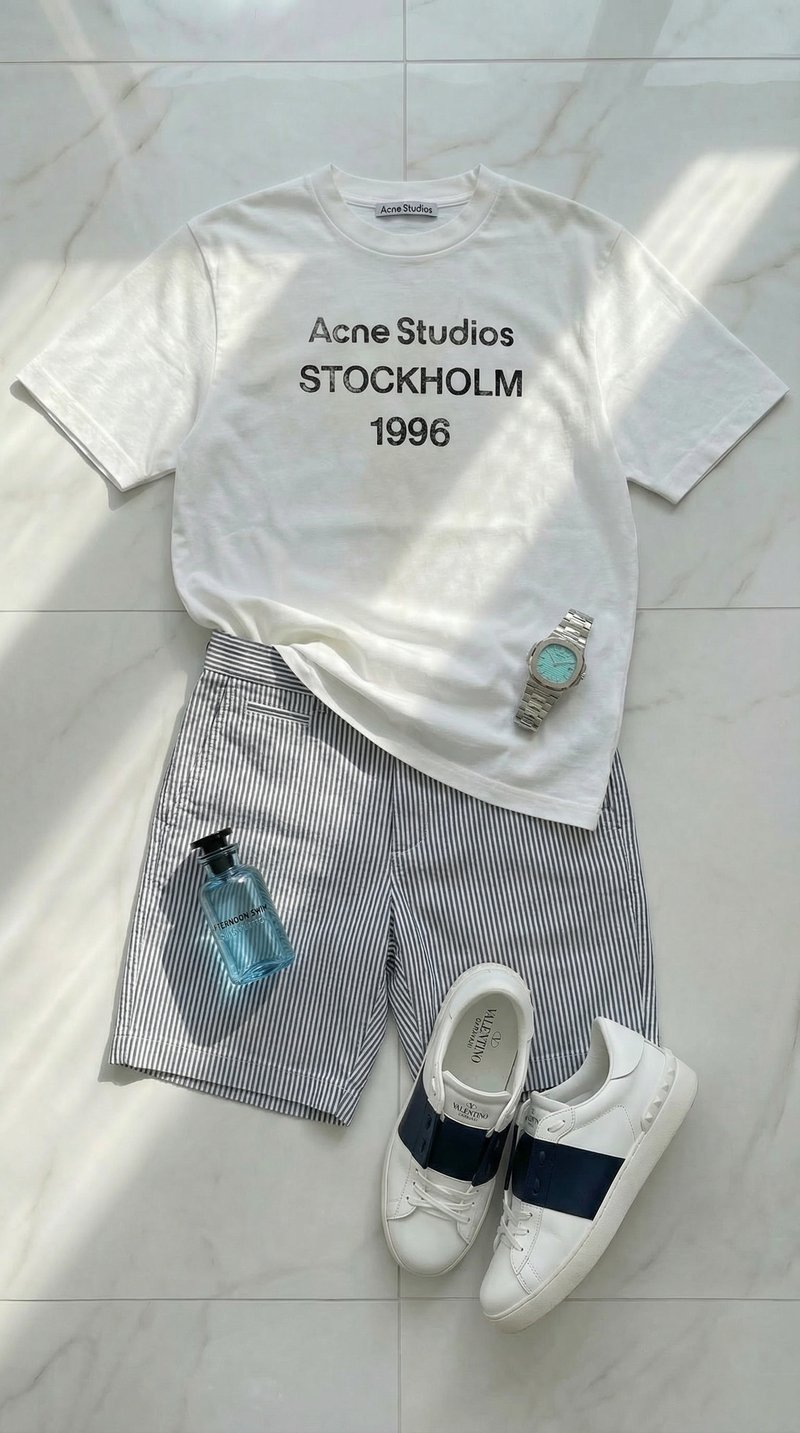 Flat-lay: Acne Studios tee, striped shorts, Patek watch and Valentino sneakers on marble